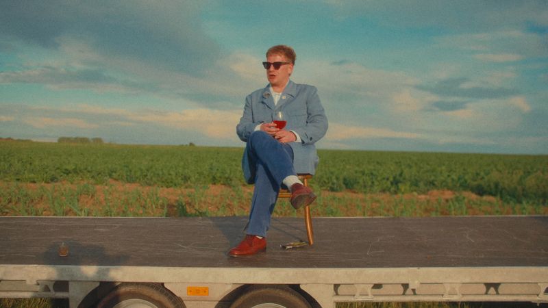 A wedding guest in a blue suit on a trailer in a field